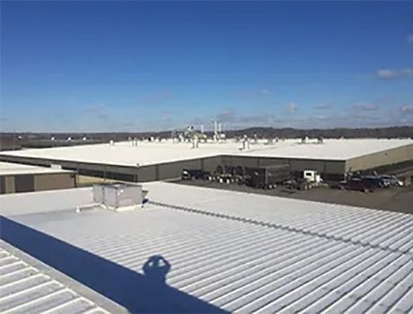 A large white roof of a building with a blue sky in the background.