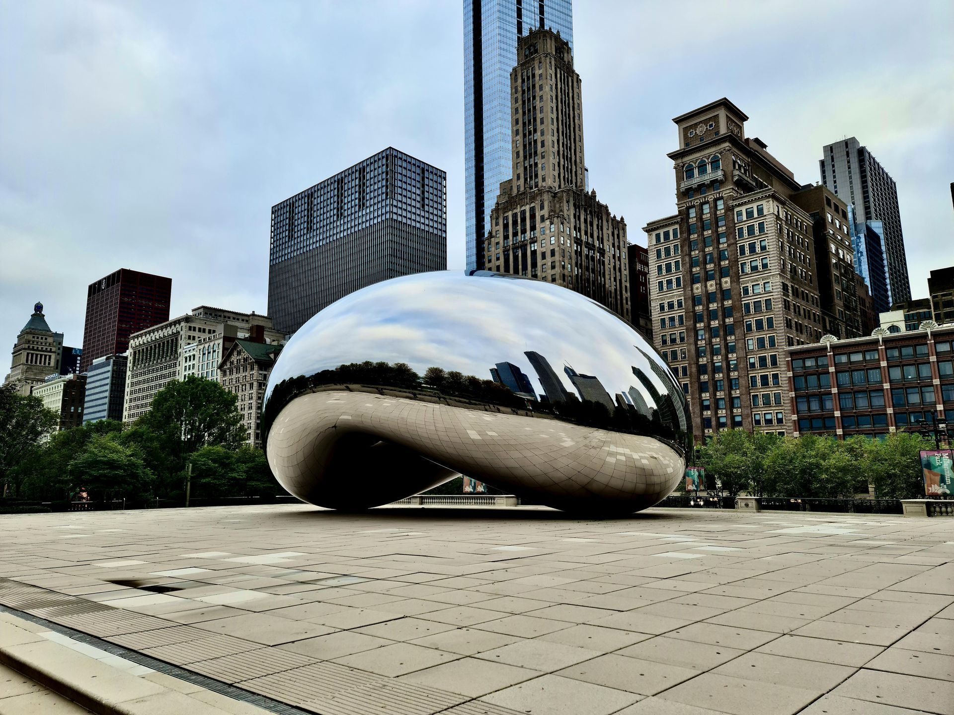 Cloud Gate “The Bean” reflecting Chicago skyline in a plaza on a cloudy day