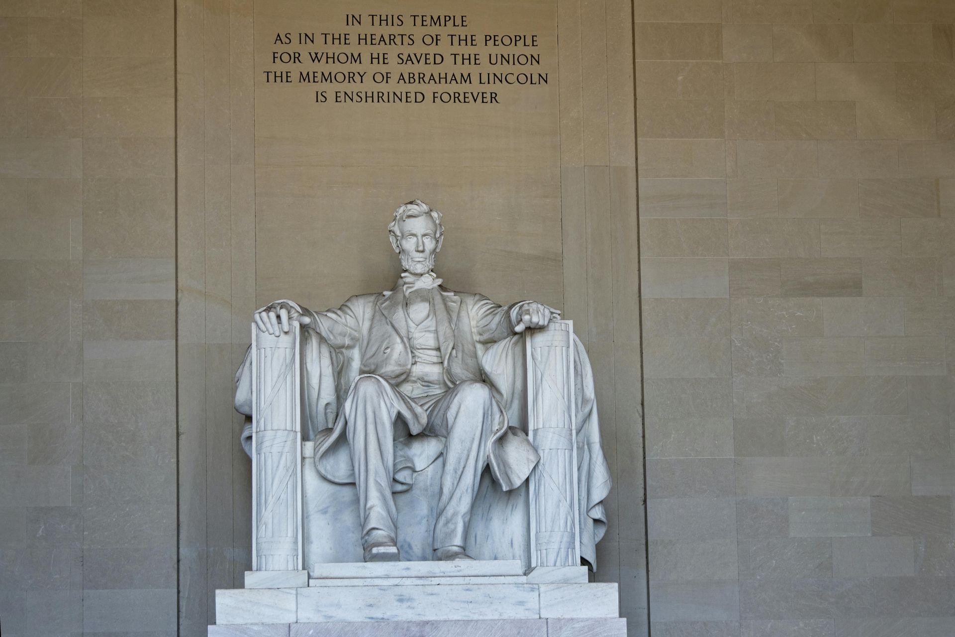 Seated marble statue of Abraham Lincoln in the Lincoln Memorial, with inscriptions above.