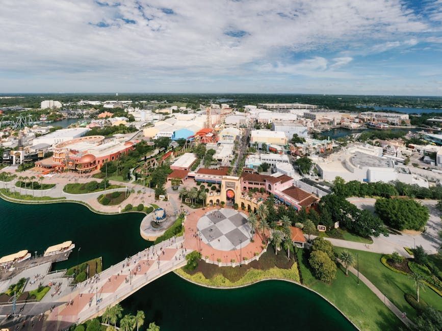 Aerial view of a waterfront theme park with buildings, paths, and a large circular pavilion.