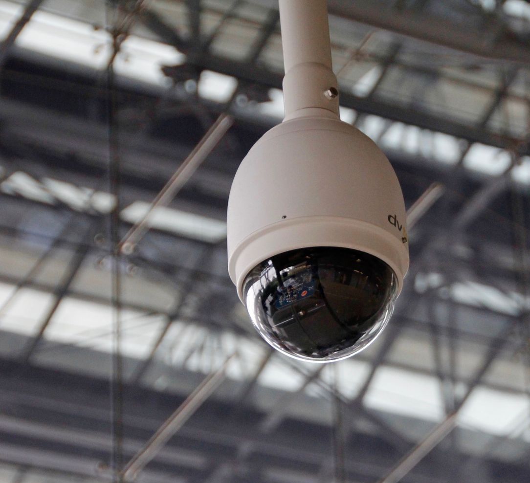 A security camera is hanging from the ceiling of a building