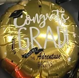 Gold graduation balloon with “Congrats Grad” and “The Adventure Begins” text