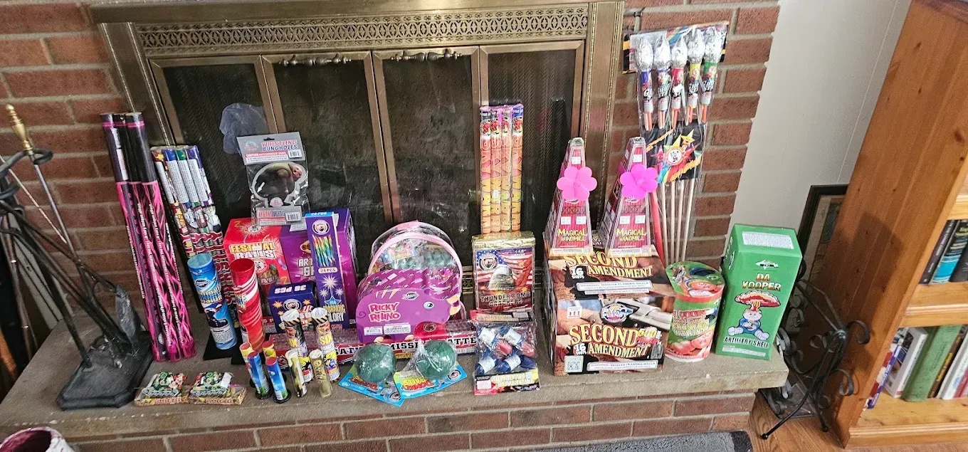 Colorful assortment of candy and snacks displayed on a fireplace hearth in front of a brick mantel