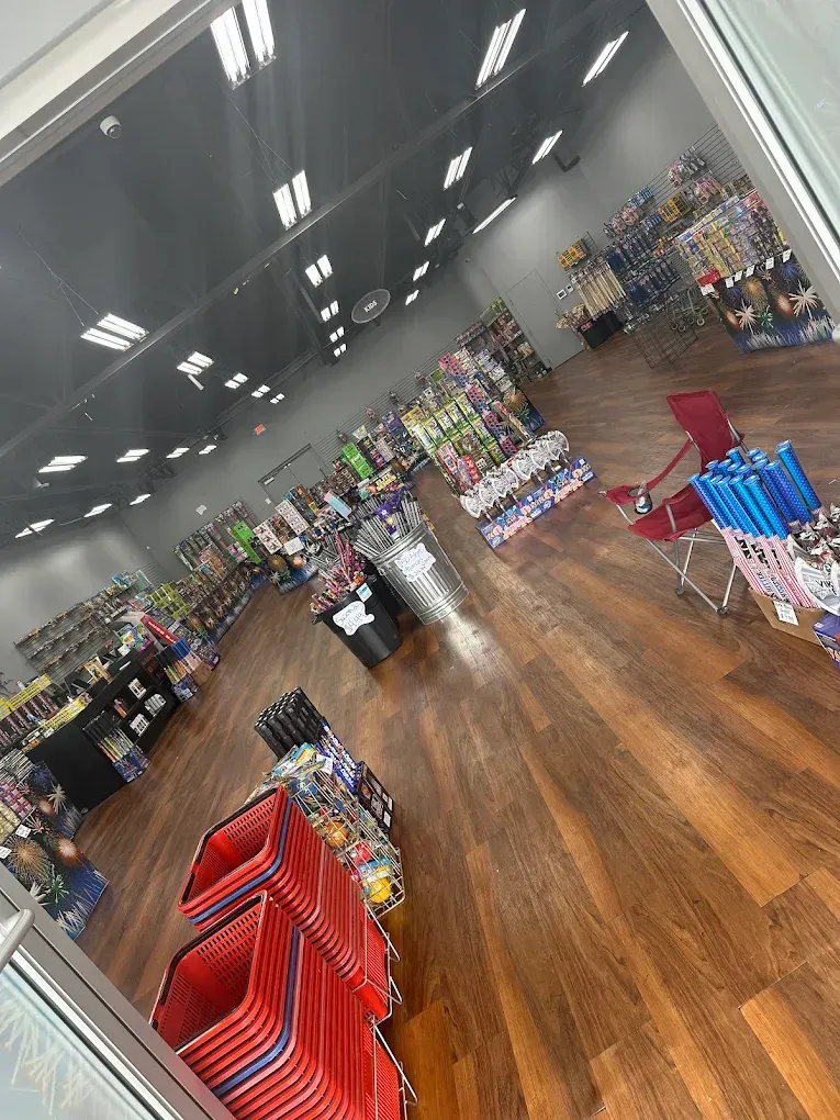 Clothing store aisle with colorful folded shirts and racks on a glossy wood floor under bright ceiling lights
