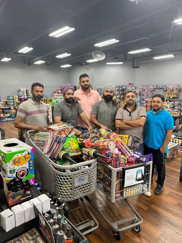 Five men stand beside carts full of colorful snacks in a store aisle.