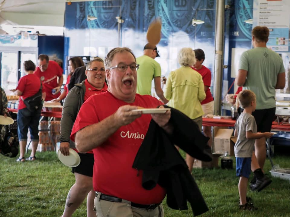 A man in a red shirt is holding a plate in his hand.
