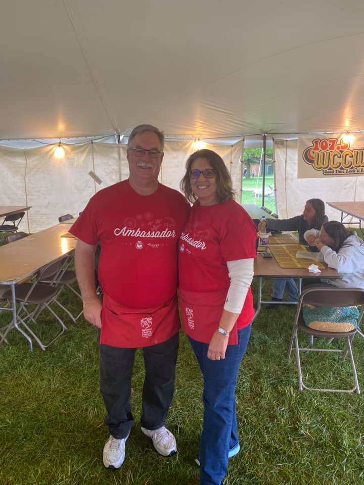 A man and a woman are posing for a picture under a tent.