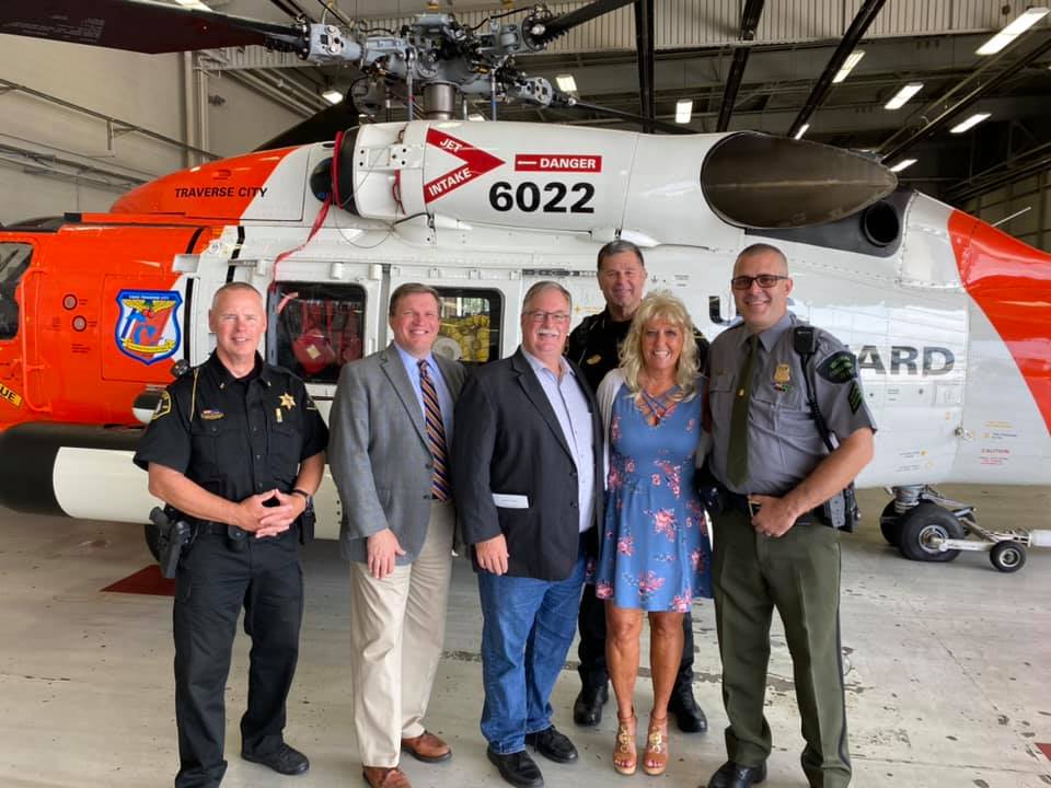 A group of people are standing in front of a helicopter.