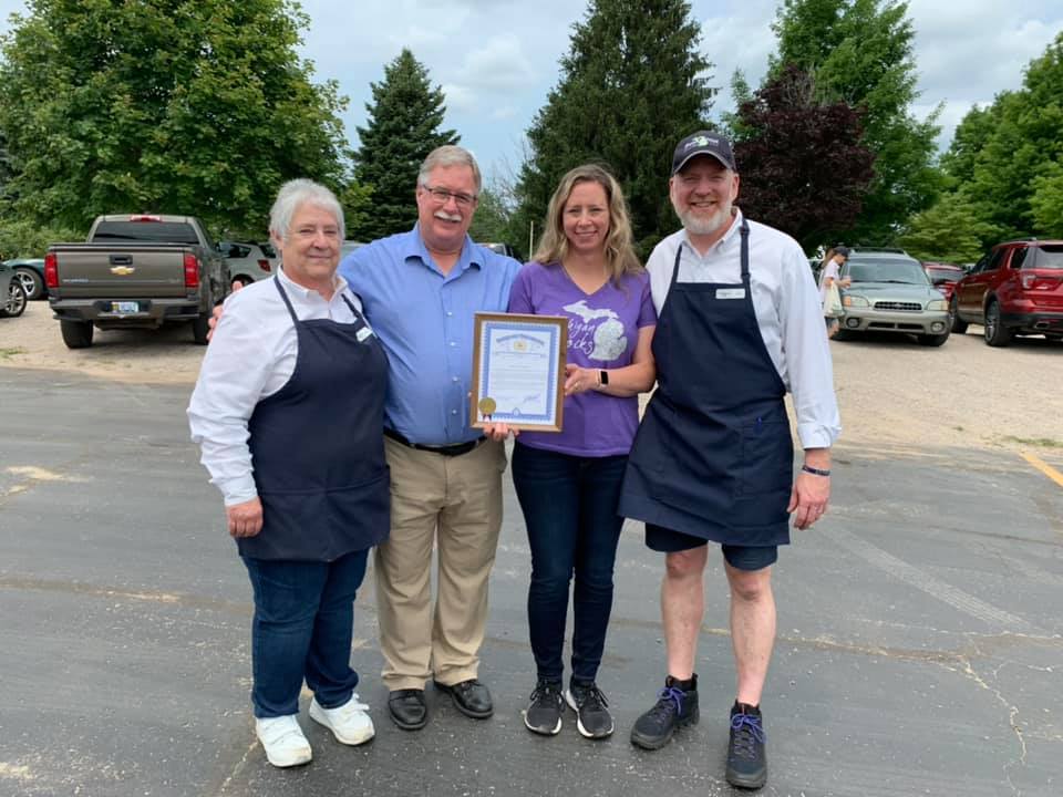 A group of people standing in a parking lot holding a certificate.