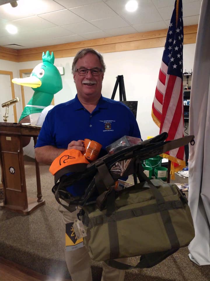 A man in a blue shirt is holding a duffel bag