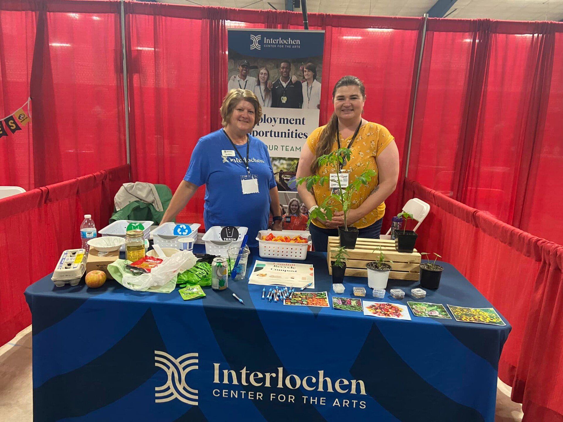 Two women are standing in front of a table that says interlochen on it.