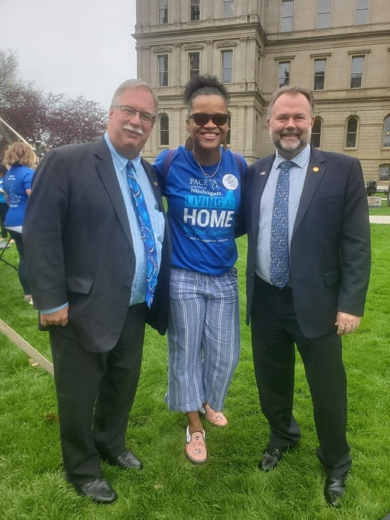 Three men and a woman are posing for a picture in front of a building.