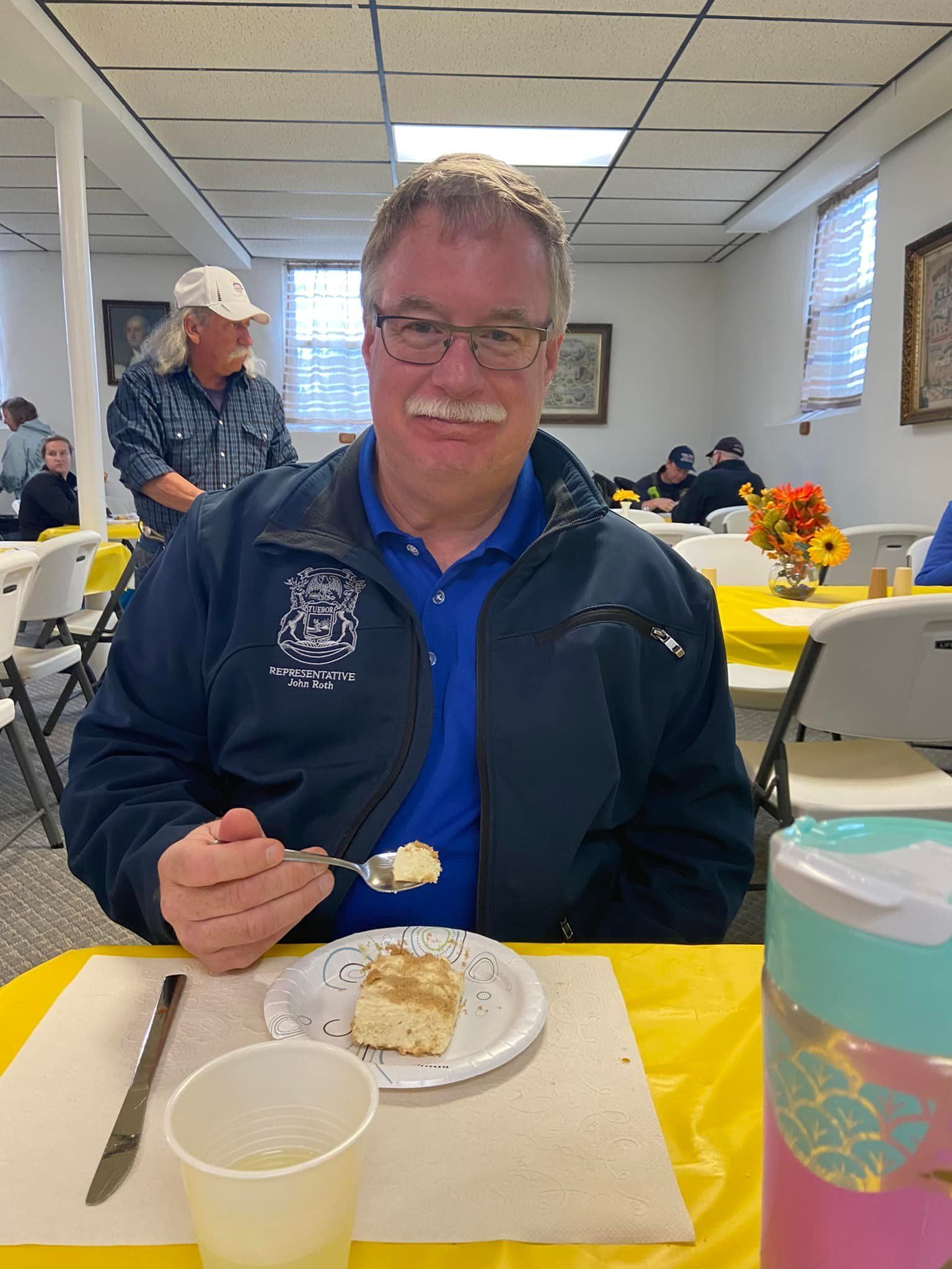 A man is sitting at a table eating a piece of cake.