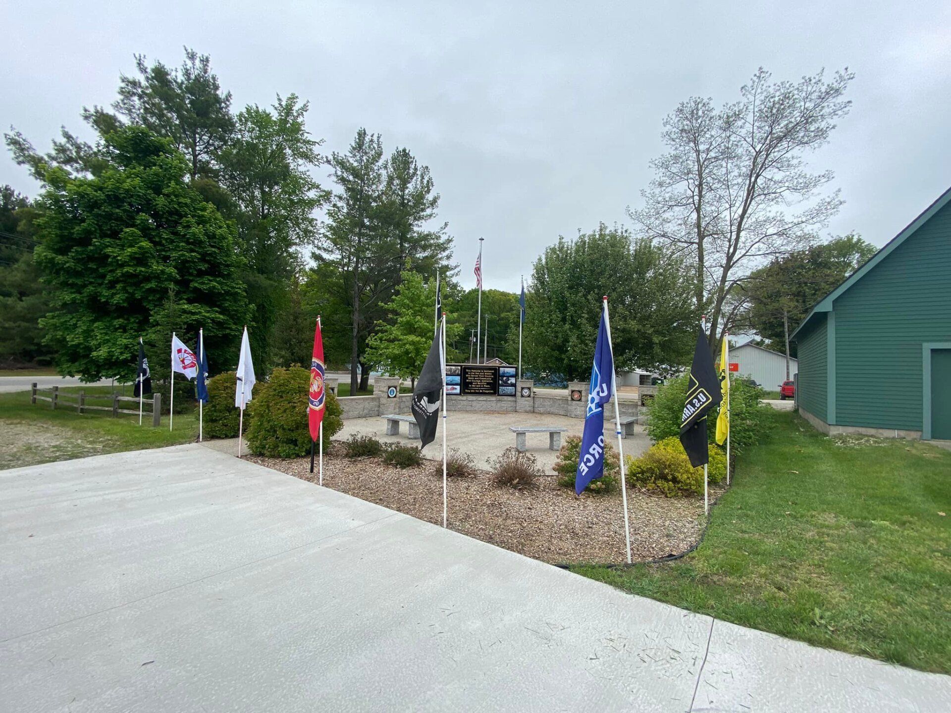 A row of flags are lined up on a sidewalk in a park.