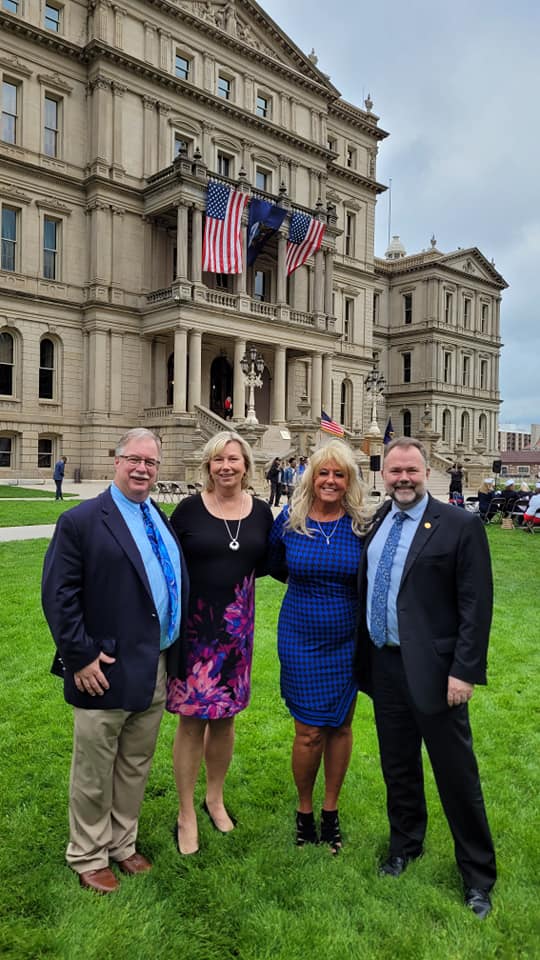 A group of people are posing for a picture in front of a large building with John Roth