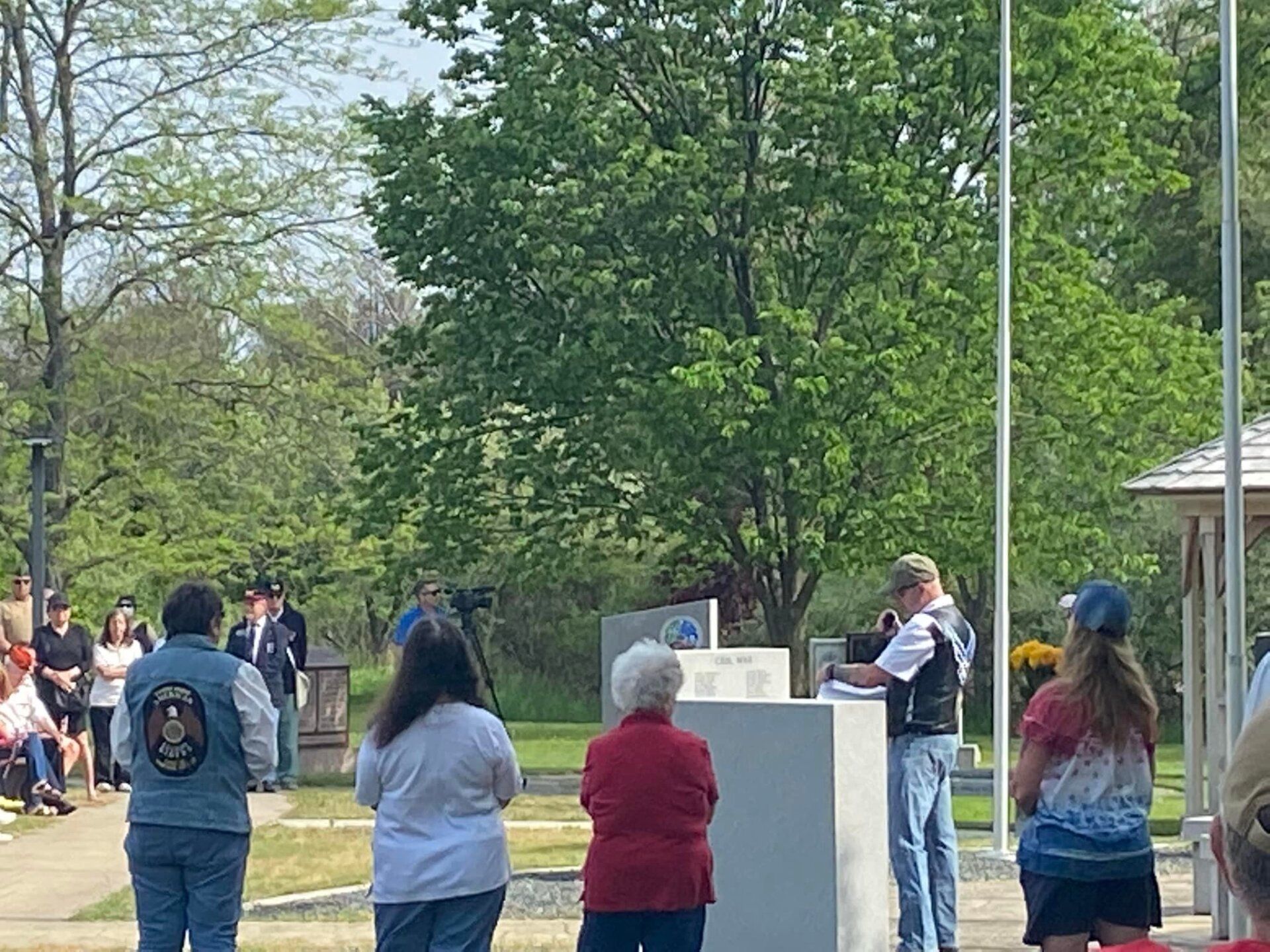A group of people are standing in front of a flag pole.