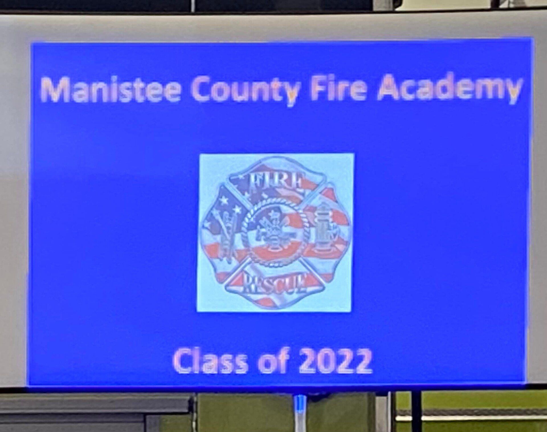 A blue sign for the manistee county fire academy class of 2022