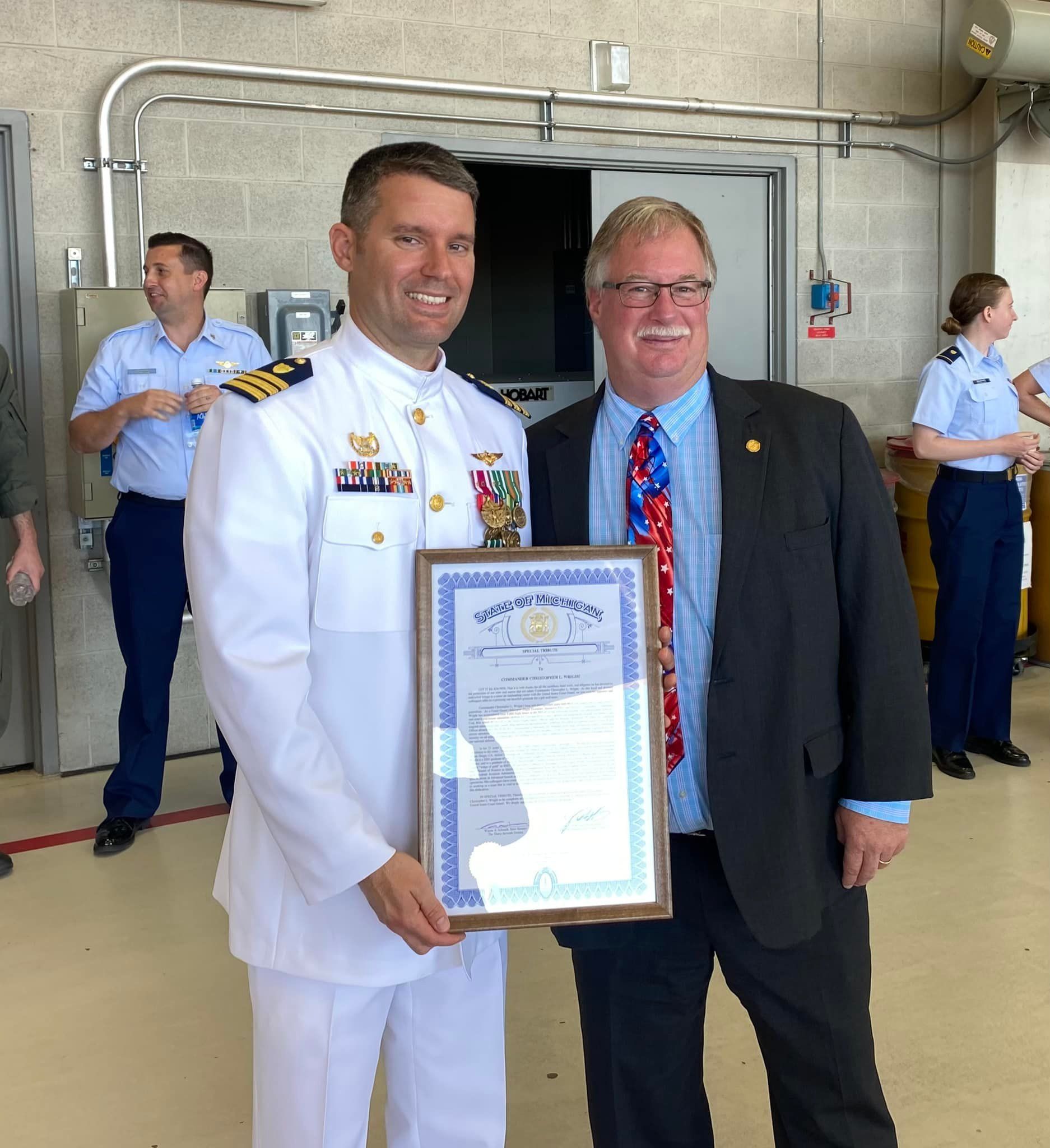 A man in a military uniform is holding a framed certificate