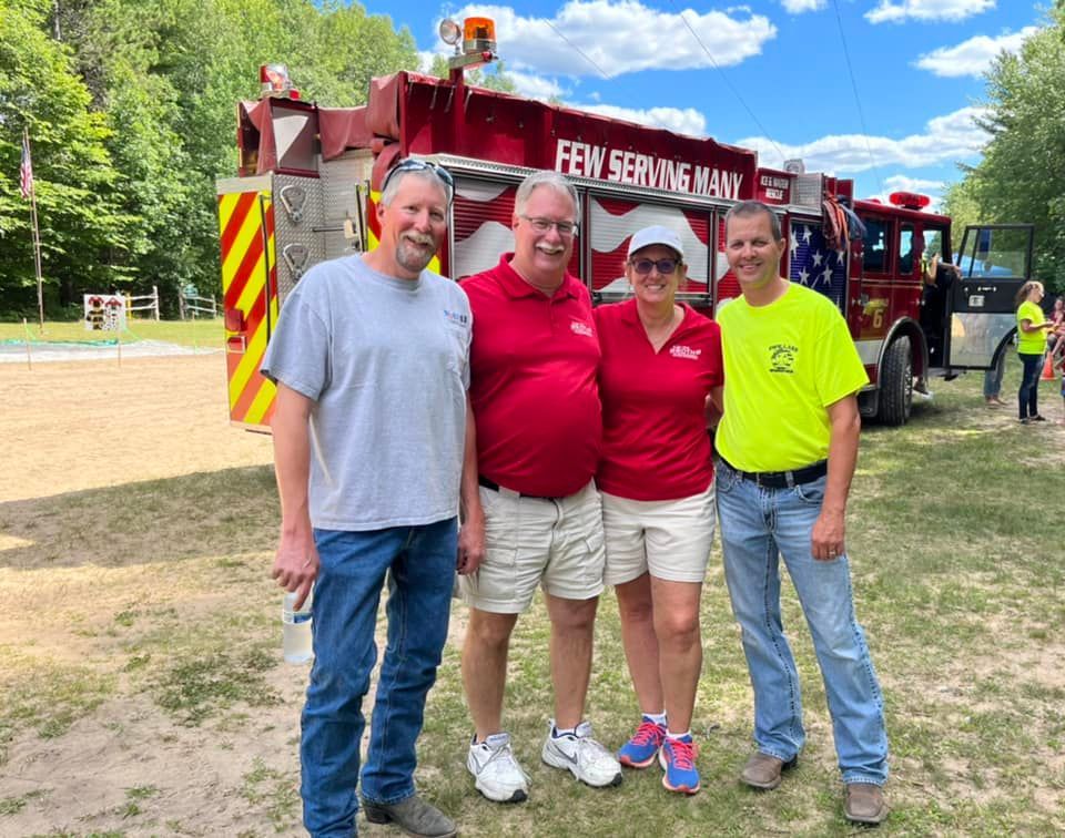 A group of people are posing for a picture in front of a fire truck. John Roth