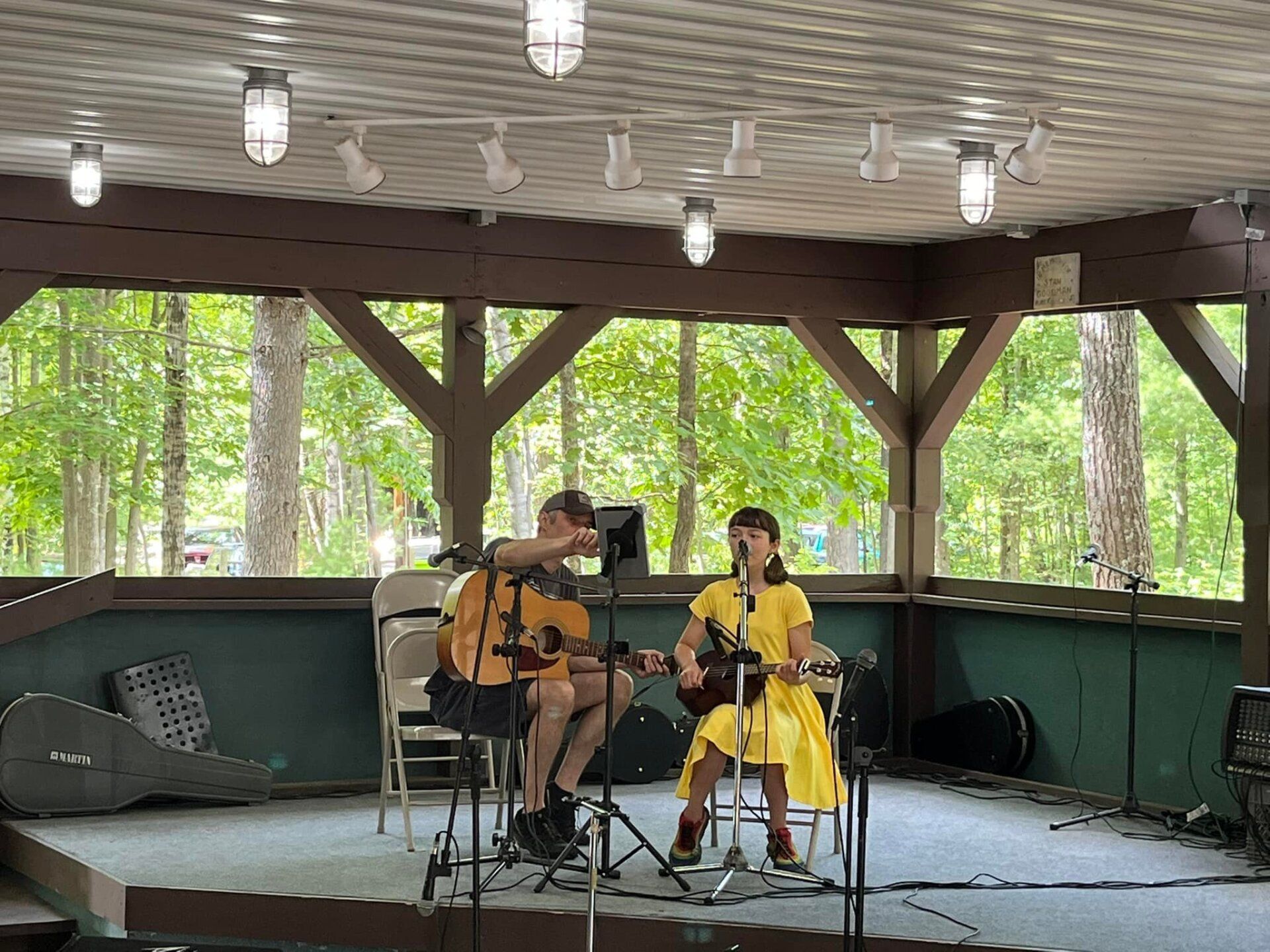 A man and a woman are playing guitars on a stage.