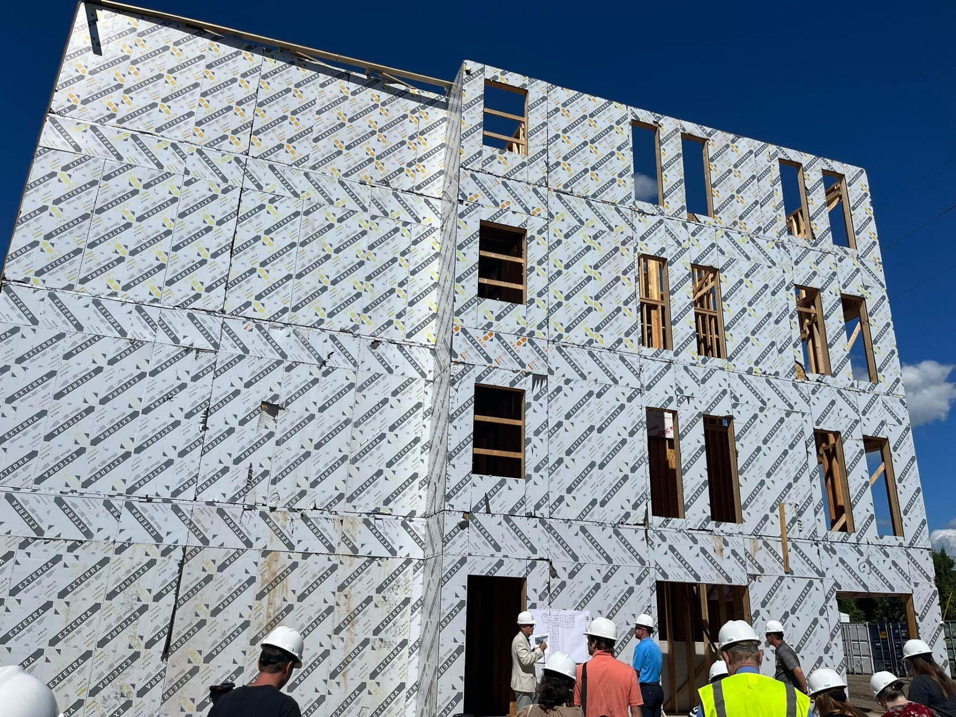 A group of construction workers are standing in front of a building under construction.