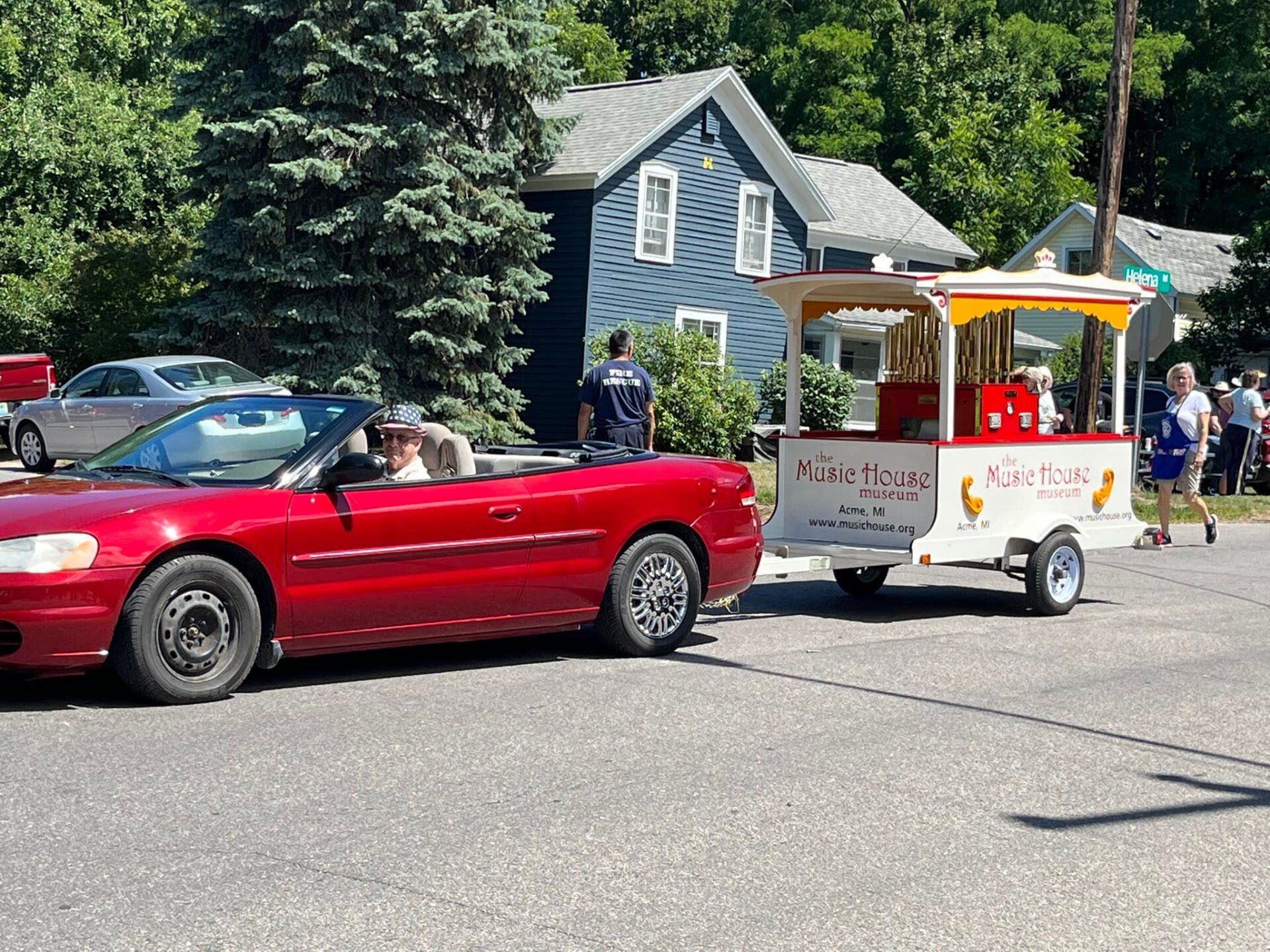A red convertible car is parked next to a popcorn cart.