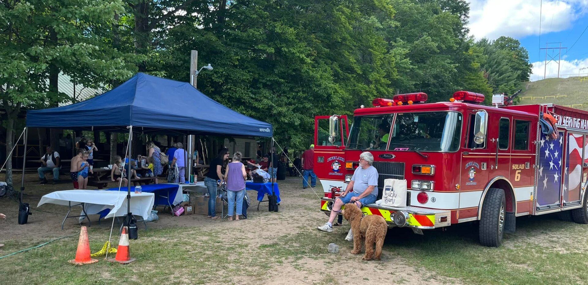 A fire truck is parked in a field next to a tent.