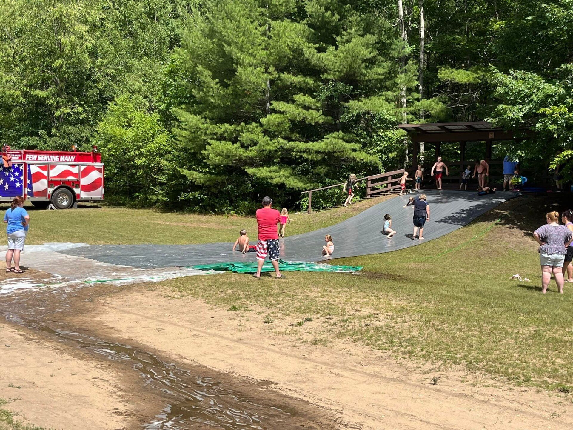 A group of people are playing in a park with a fire truck in the background.