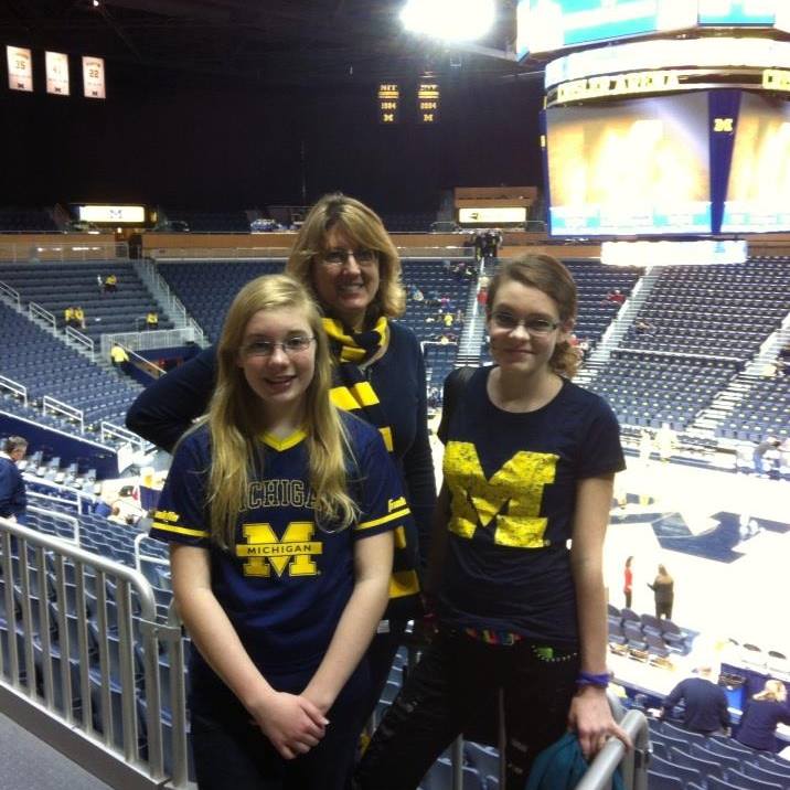 Three girls wearing michigan shirts are posing for a picture