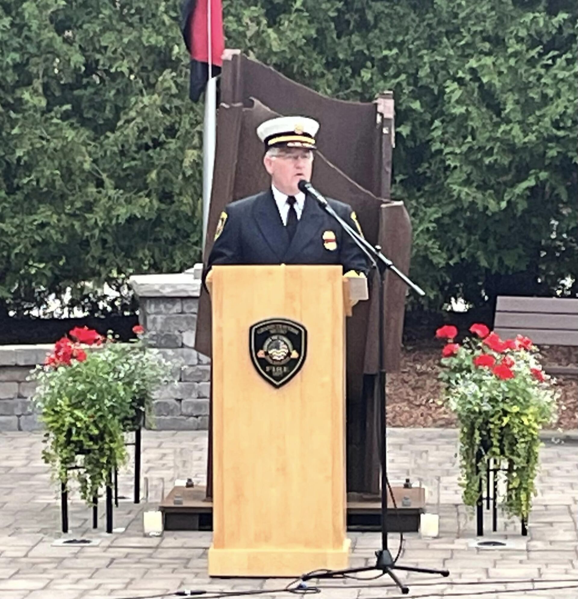 A man in a uniform stands at a podium speaking into a microphone