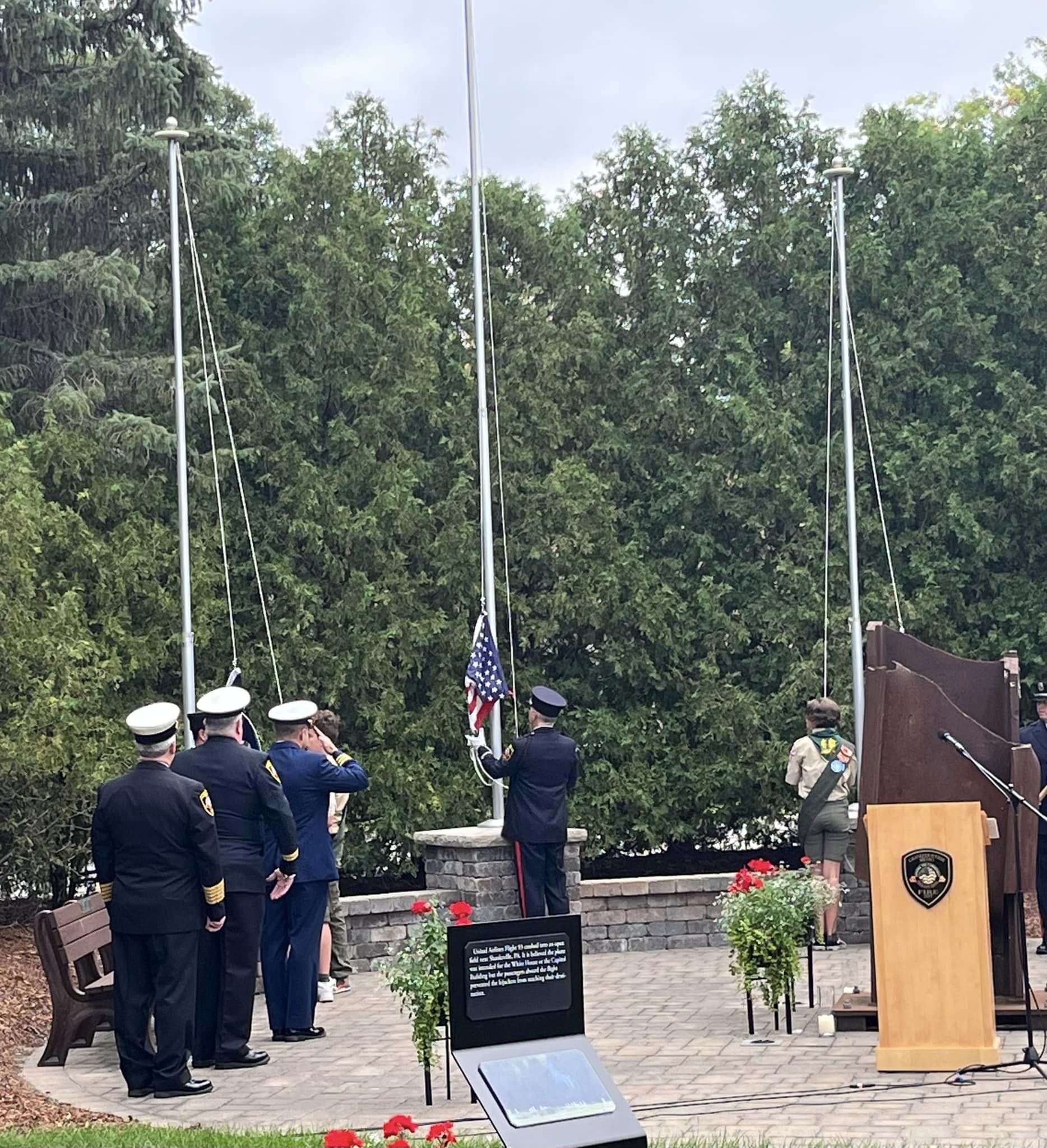 A group of men in uniforms are standing around a flag pole.