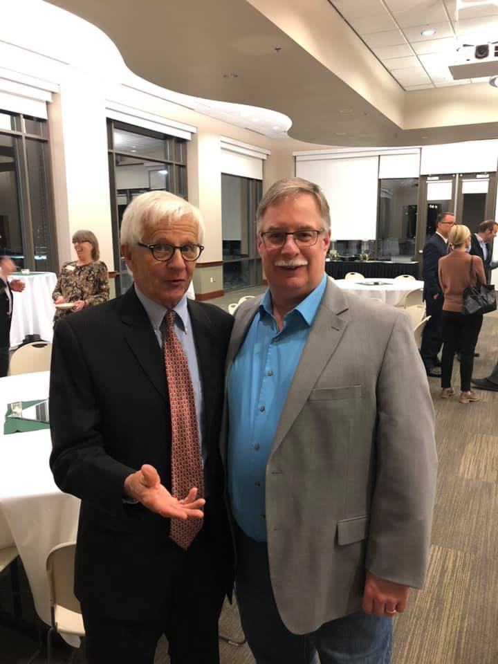 Two men in suits and ties are posing for a picture in a room.