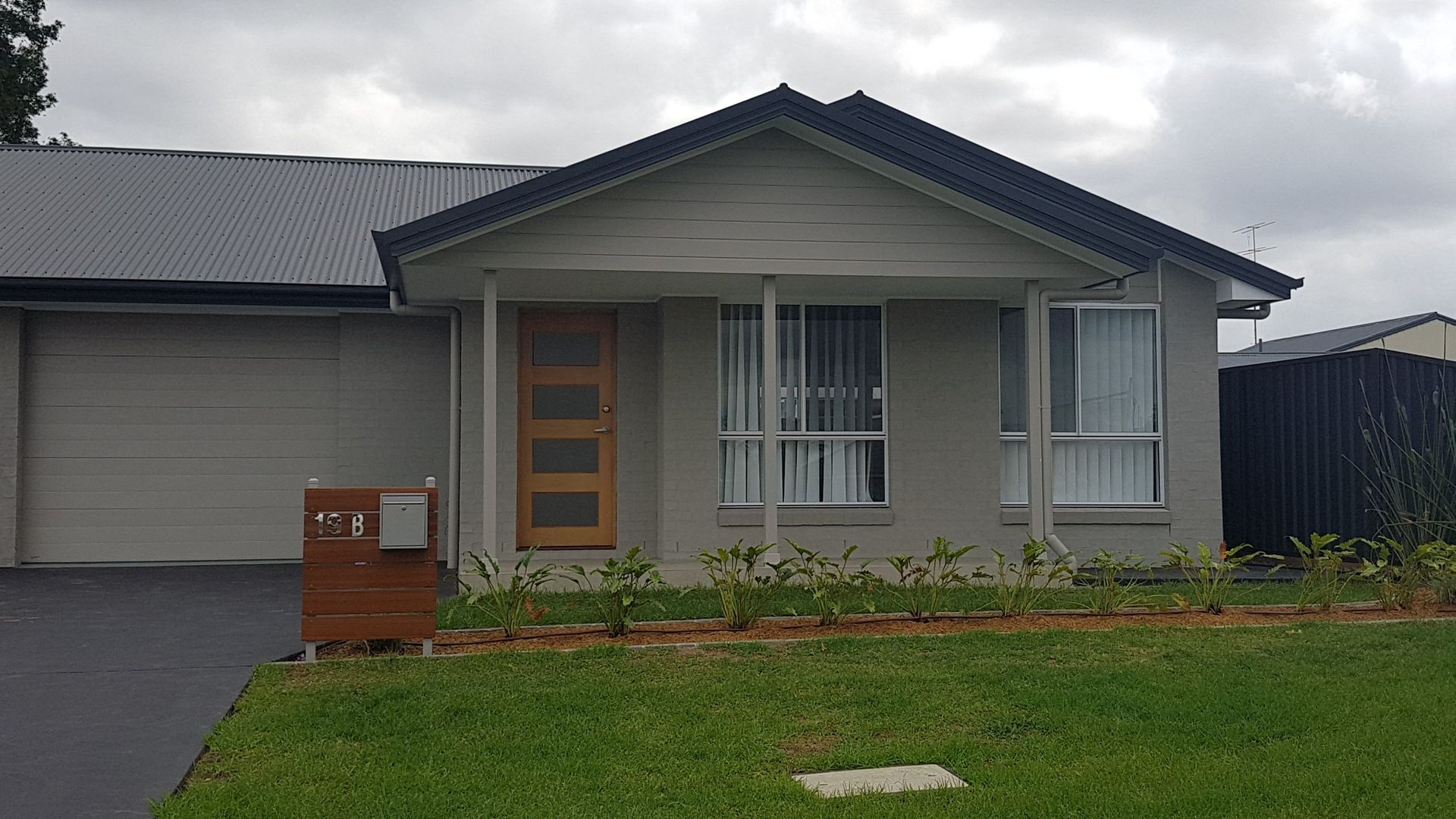 Gray house with a dark roof and a small porch. A mailbox is to the left.