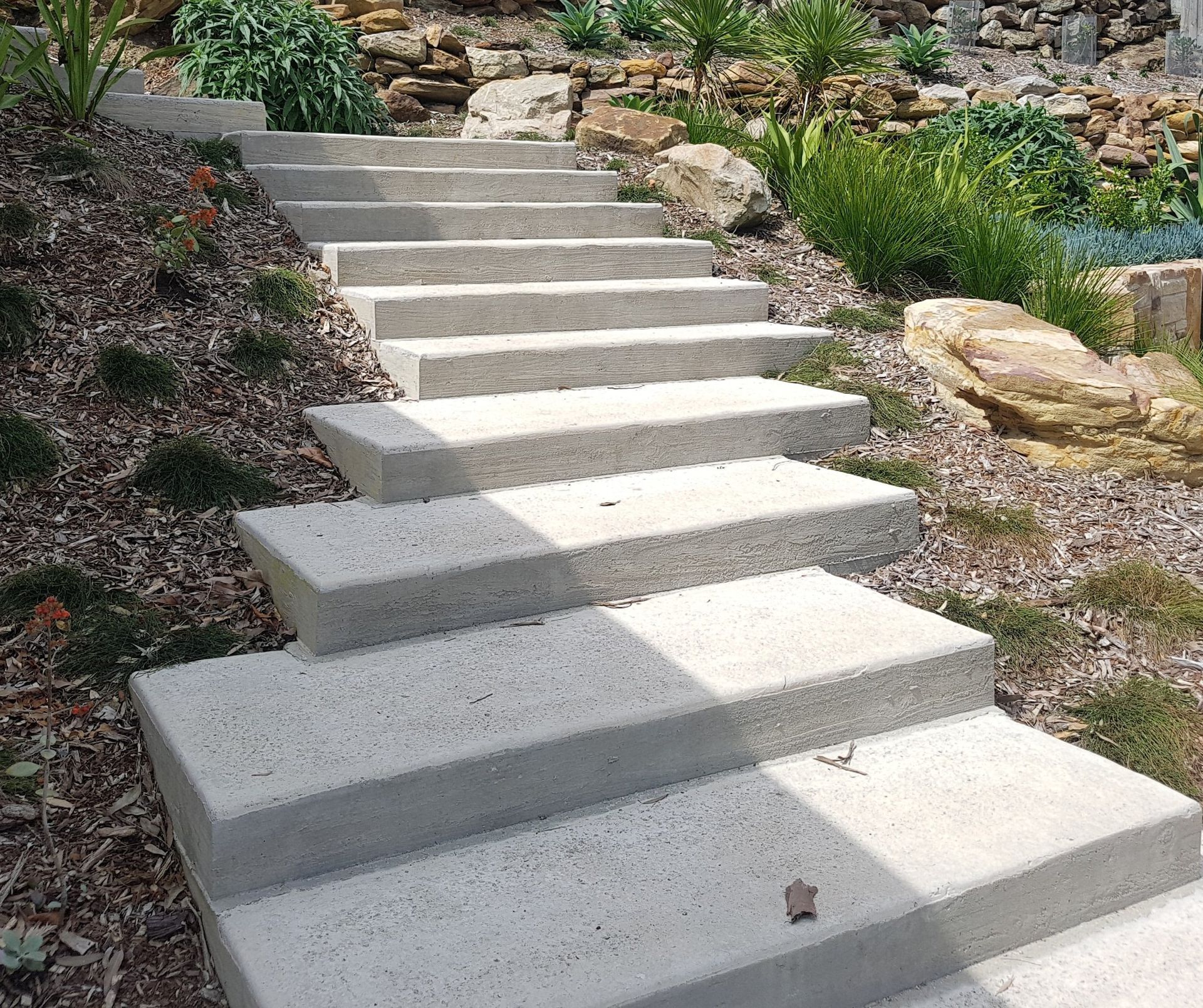 Concrete stairs leading up a hillside garden.