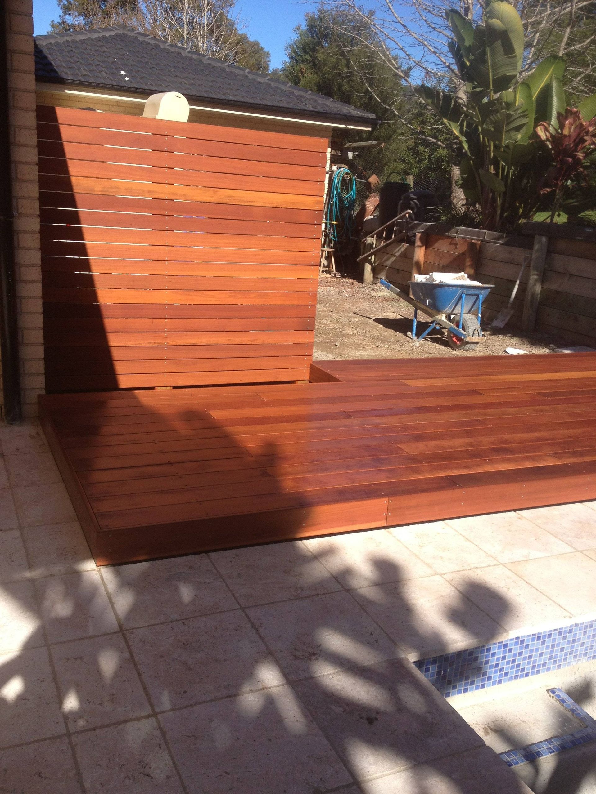 Wooden deck and privacy screen in backyard, sunny day.