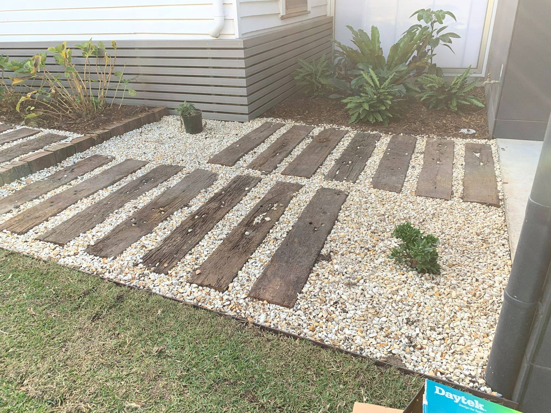 Wooden planks pathway through gravel landscaping.