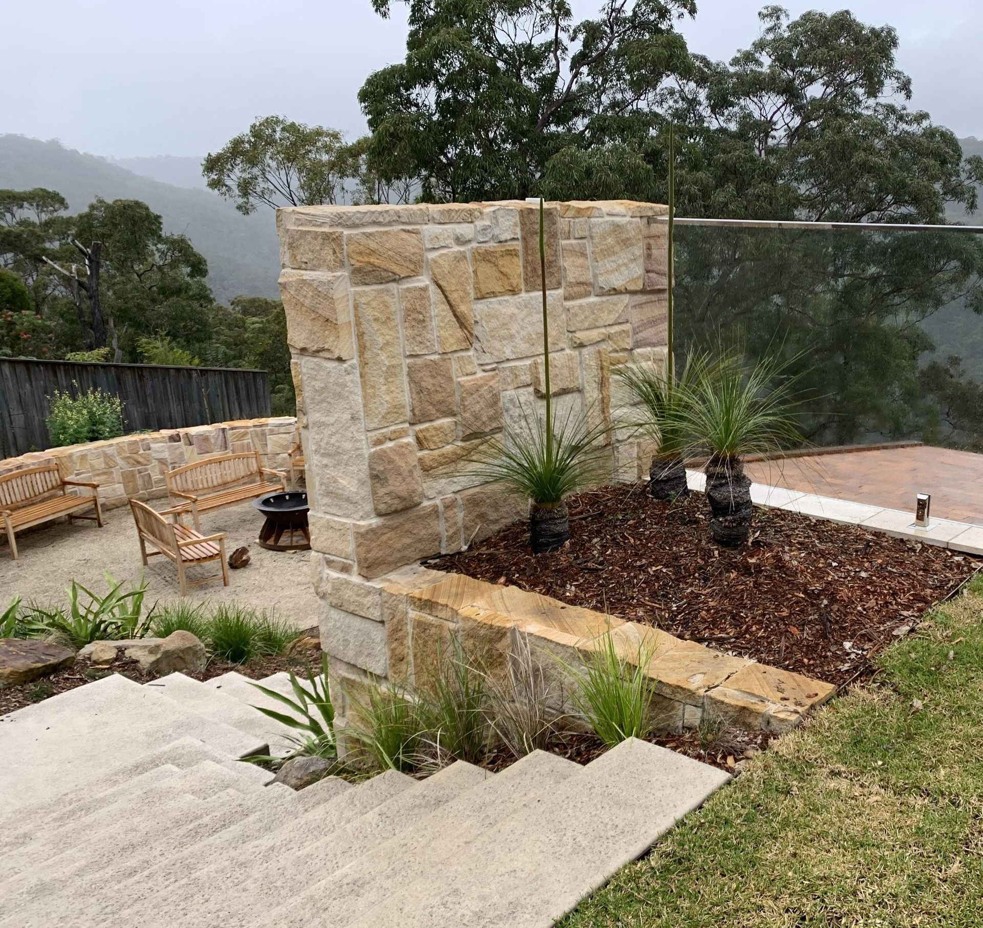 Stone wall with landscaping, patio seating, and scenic mountain views.