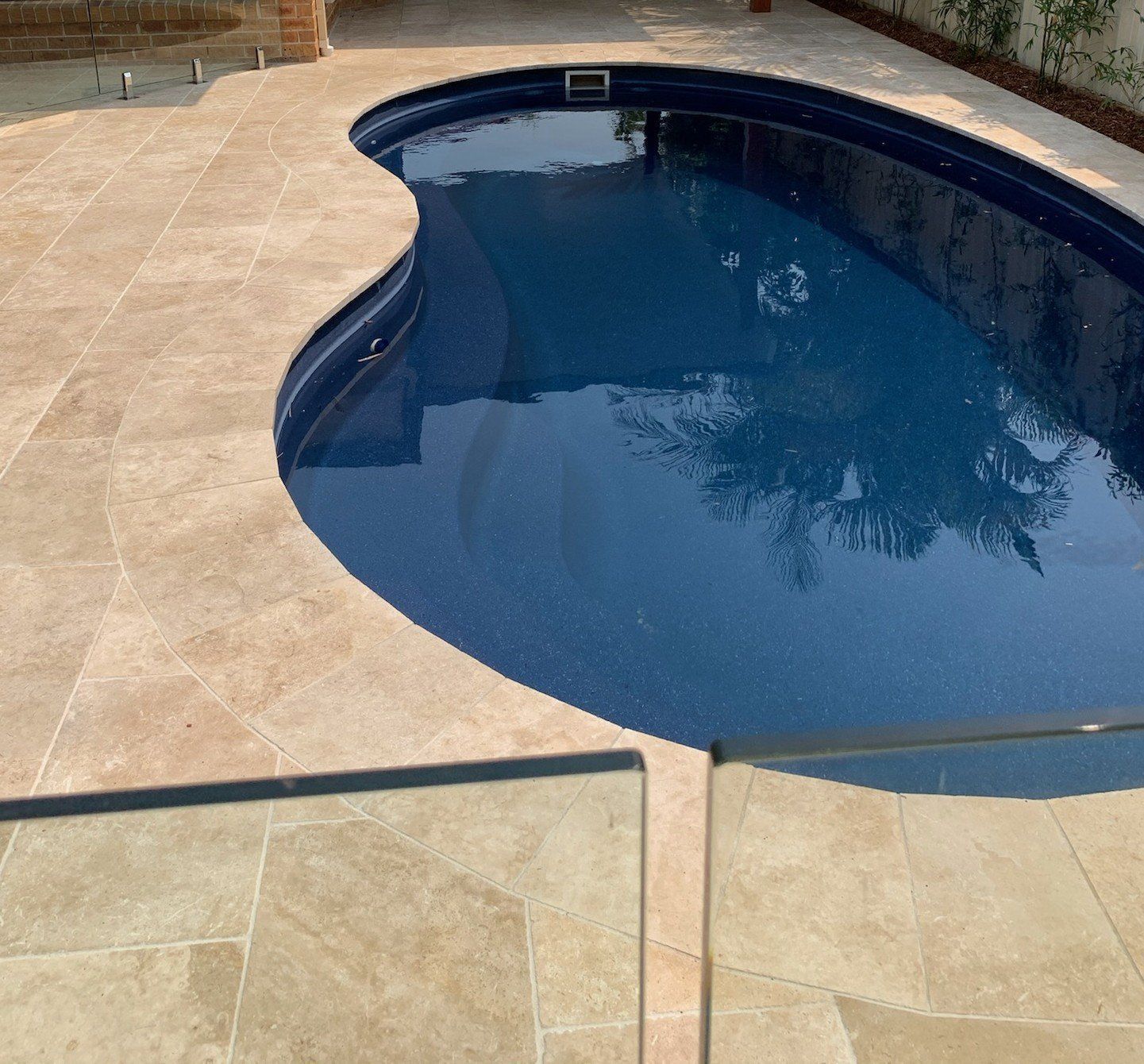 Swimming pool with blue water and tan stone surround.