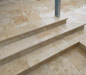 Steps made of light-colored stone tiles leading up, with a wet, reflective surface.