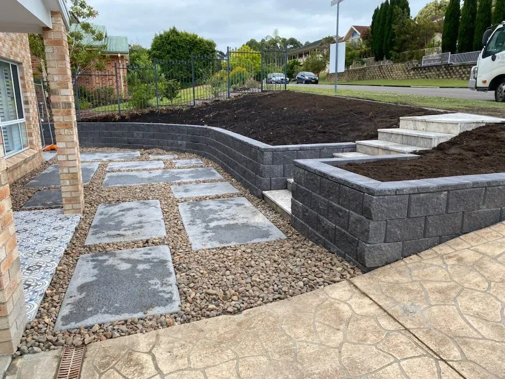 Pathway with large stone steps and retaining walls, leading to house with landscaping.