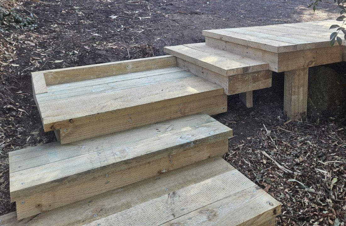 Wooden outdoor steps built on ground, angled and flat sections.