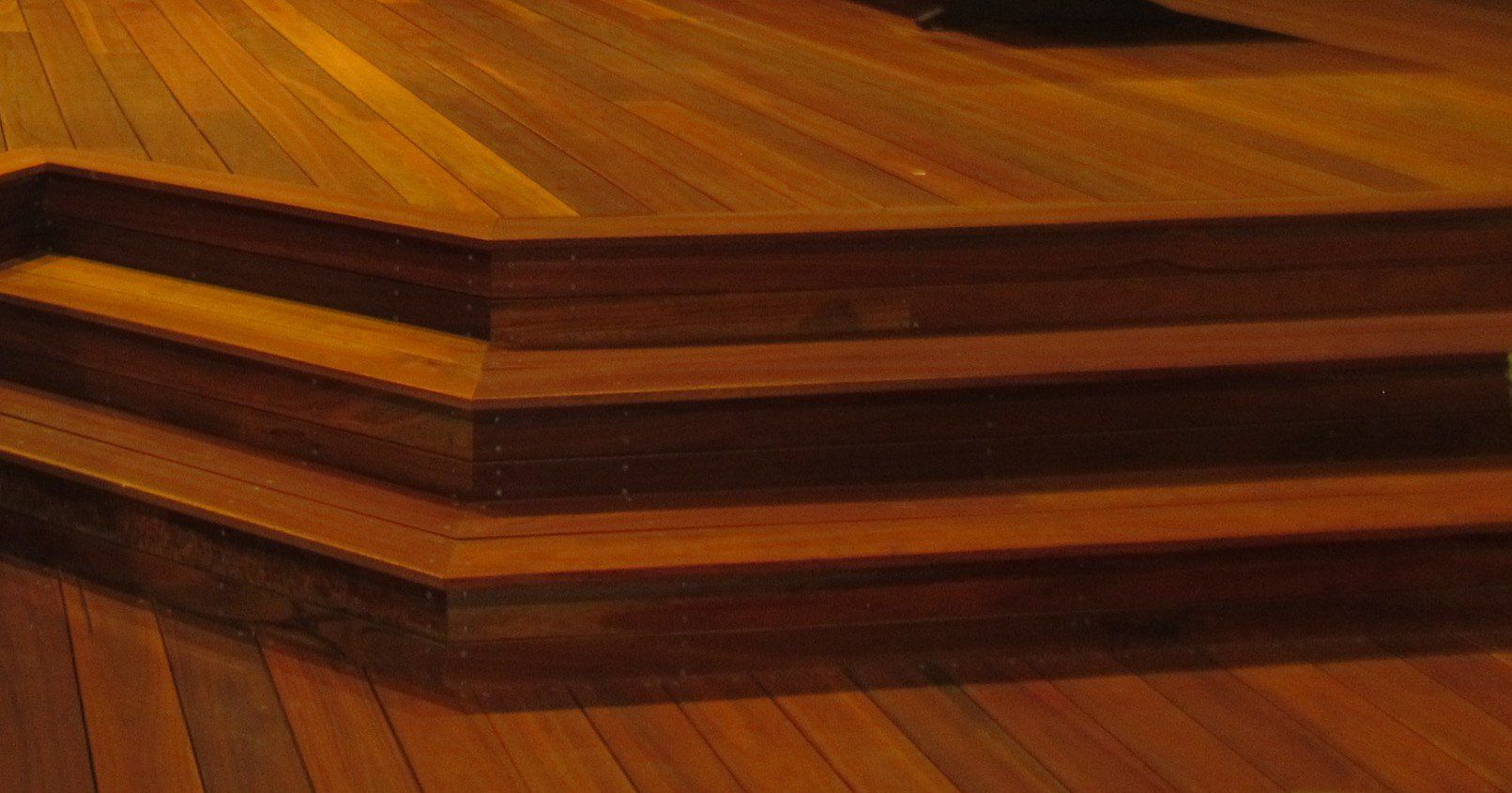 Wooden steps leading upwards, stained a rich brown, built into a wooden floor.