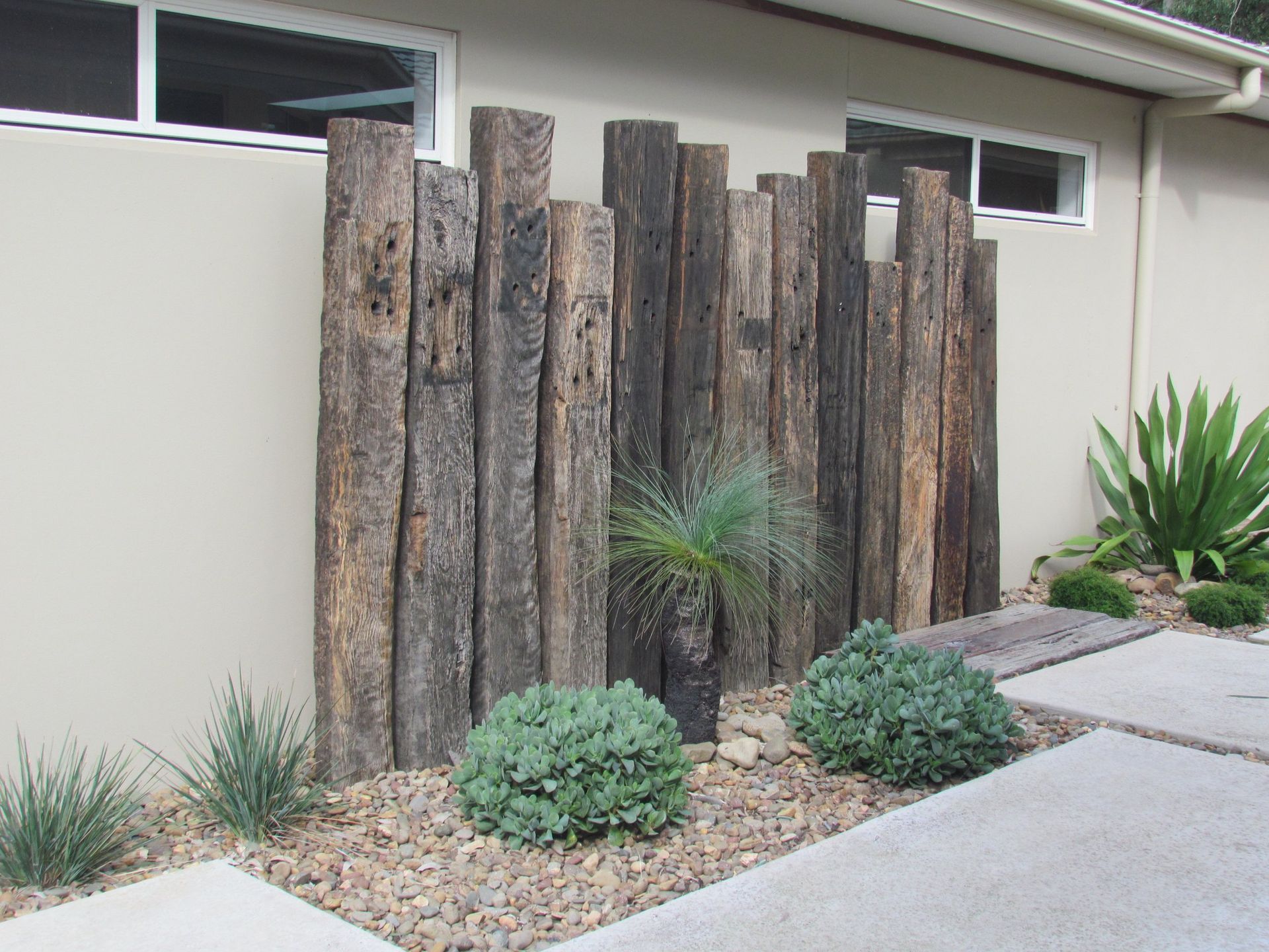 Wooden posts create a screen in a landscaped yard.