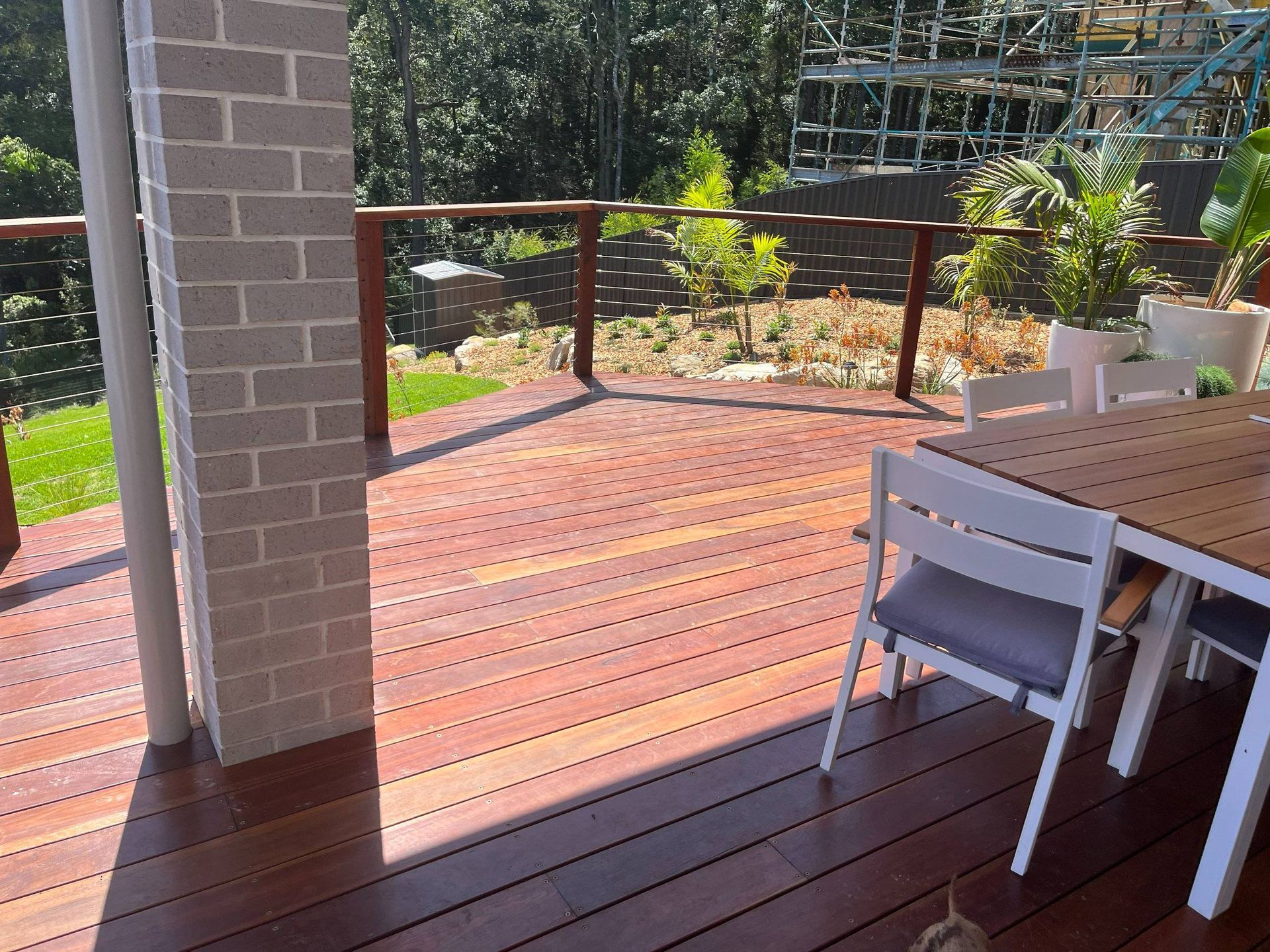 Wooden deck with outdoor furniture, brick pillar, and garden backdrop.