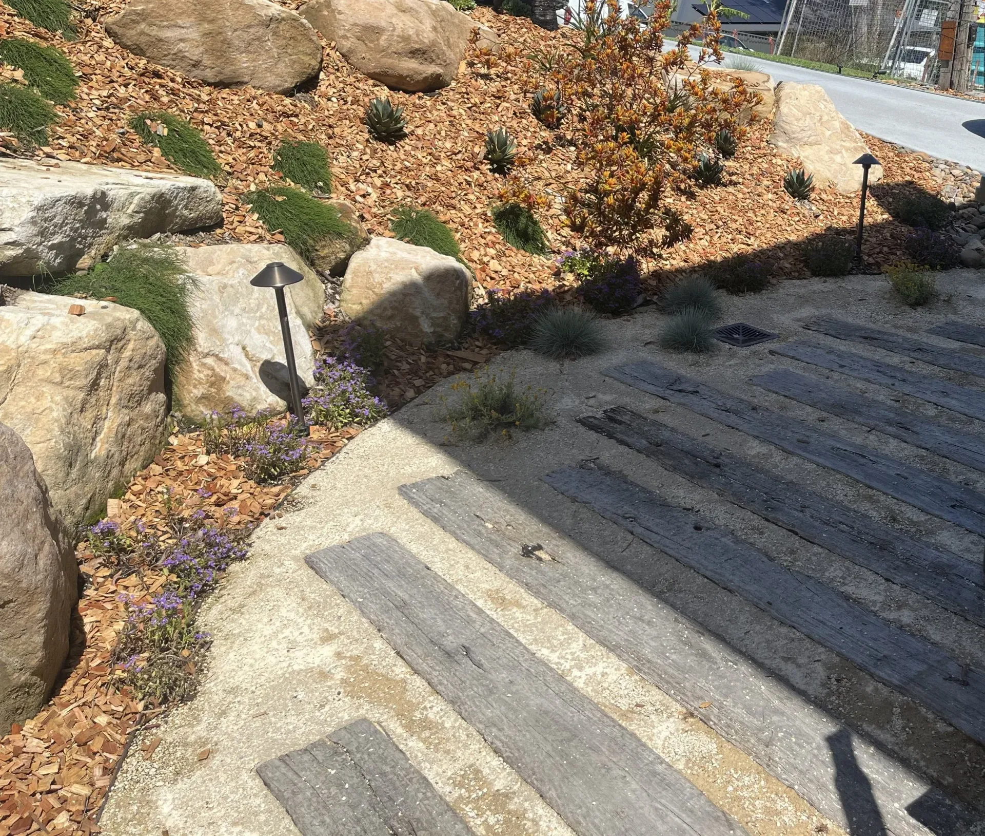 Stone steps and landscaping with boulders, mulch, and greenery.