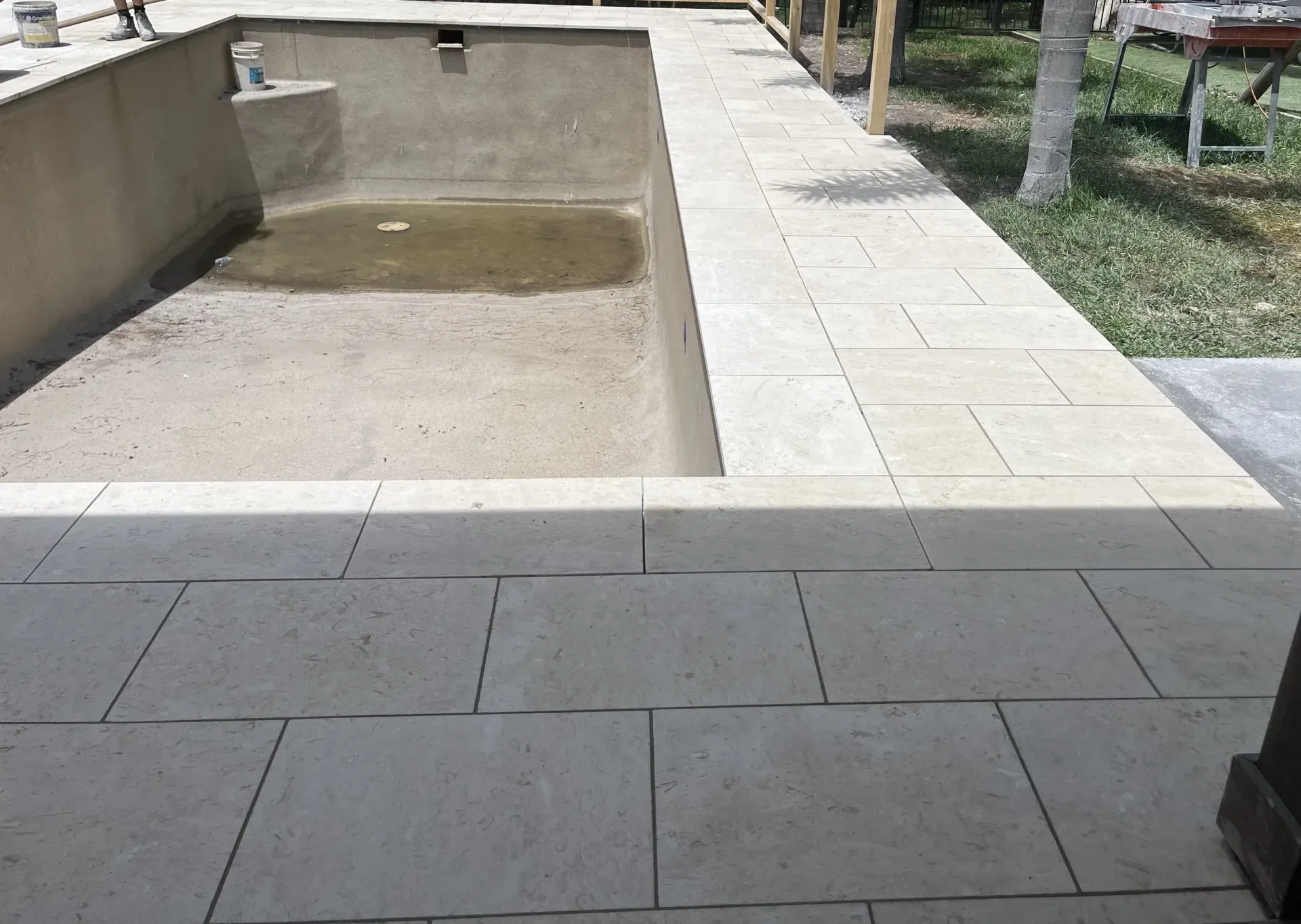 Empty swimming pool under construction with stone tiling.