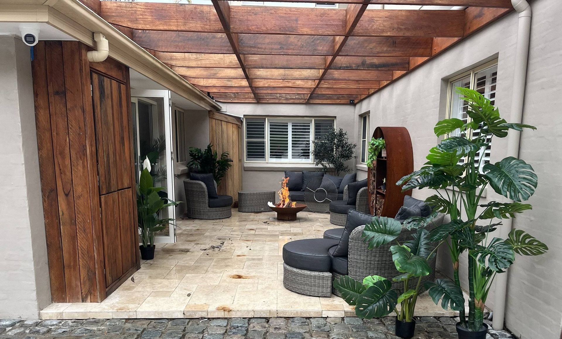 Outdoor patio with seating, fire pit, and wood pergola.