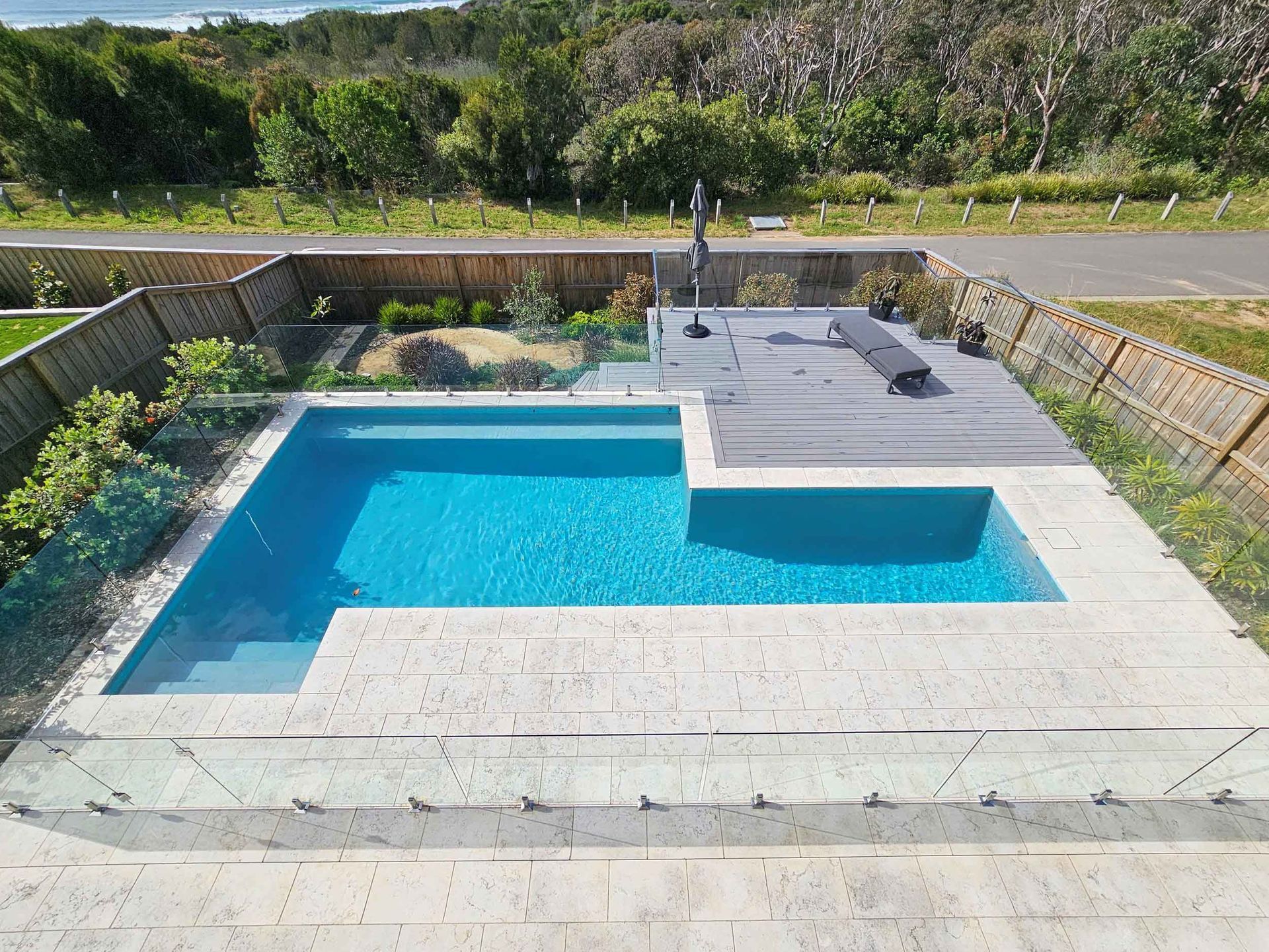 A rectangular swimming pool with turquoise water and a raised, tiled area.