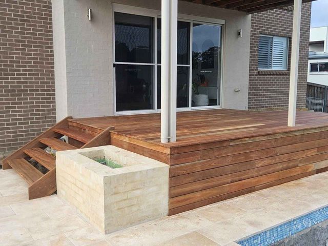 Wooden deck with stairs, built-in planter, and sliding glass doors.  Exterior with brick and stone.