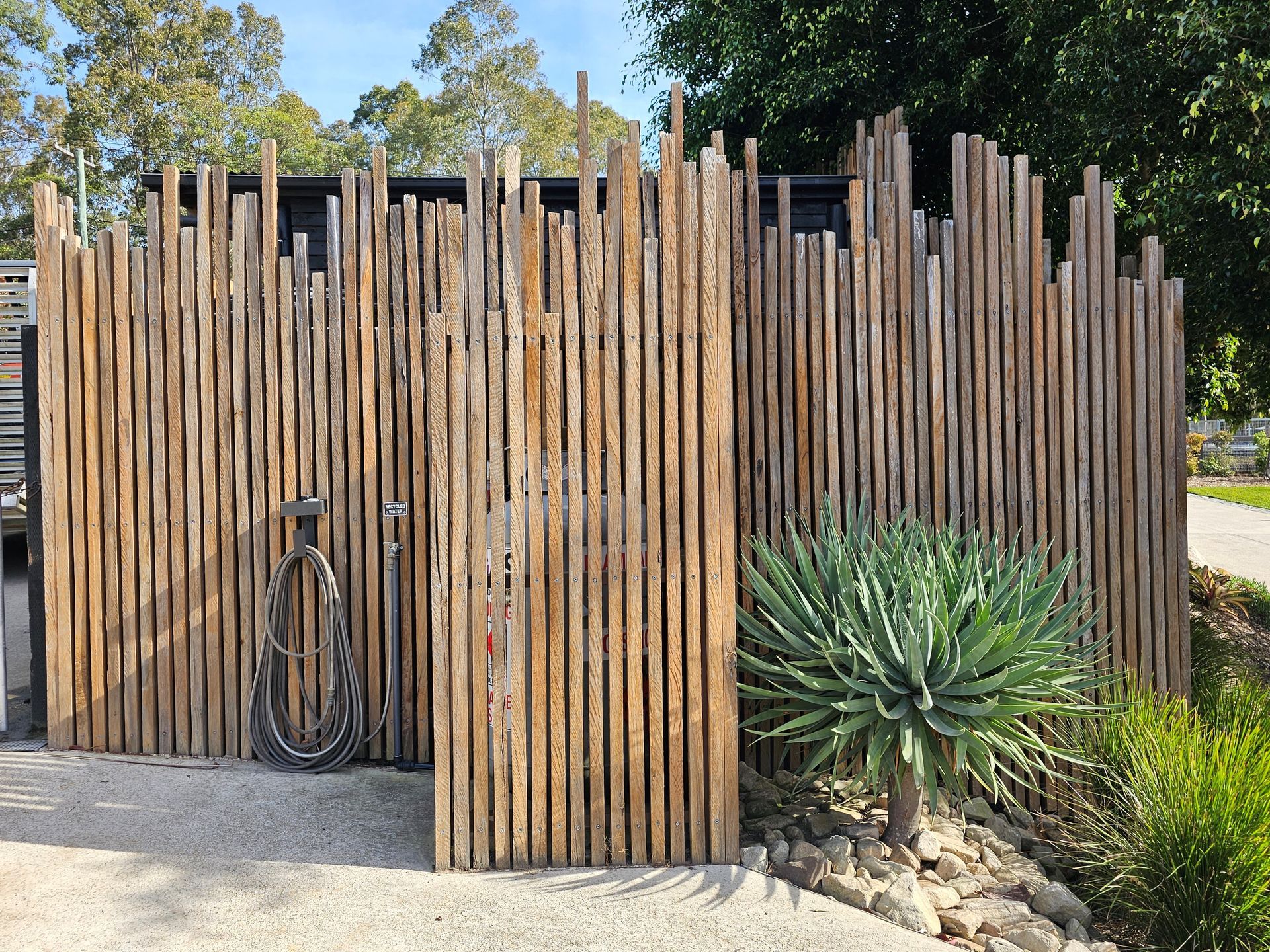 Construction site with gray cinder block retaining walls and a tree. A two-story building is in the background.